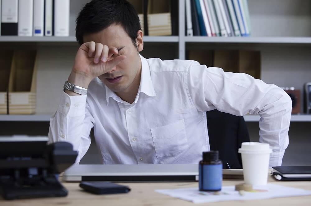 過重労働によって疲労している人のイメージ
